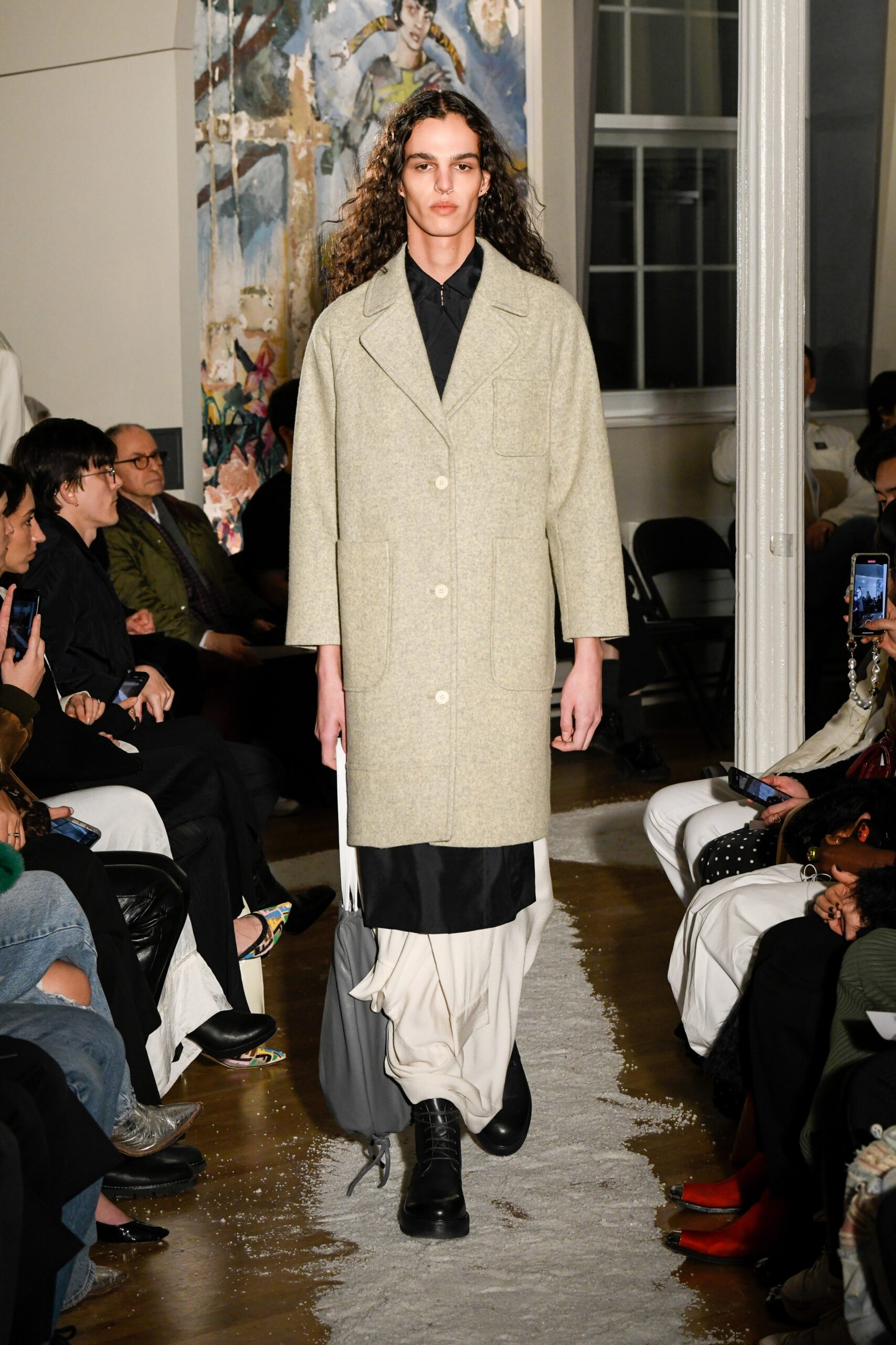 A relaxed beige wool coat layered over a black dress with long sleeves and a collared design.