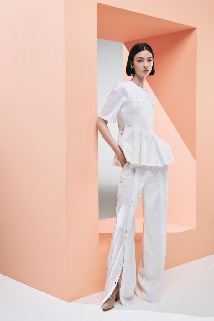 A relaxed white top with short sleeves and a V-neck paired with wide-leg pants.