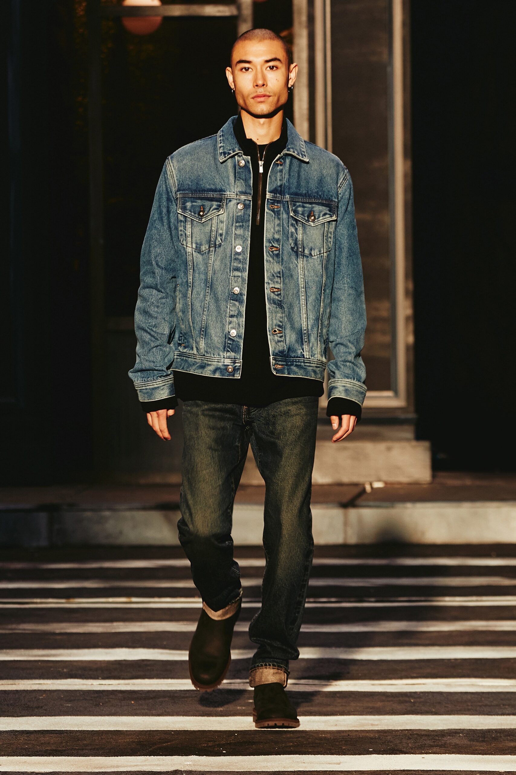 A relaxed blue denim jacket paired with black straight-leg pants, featuring a collared design.