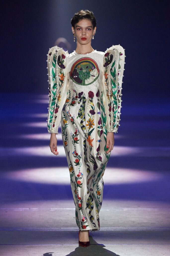 A fitted white dress with long sleeves, high neckline, and intricate embroidery.
