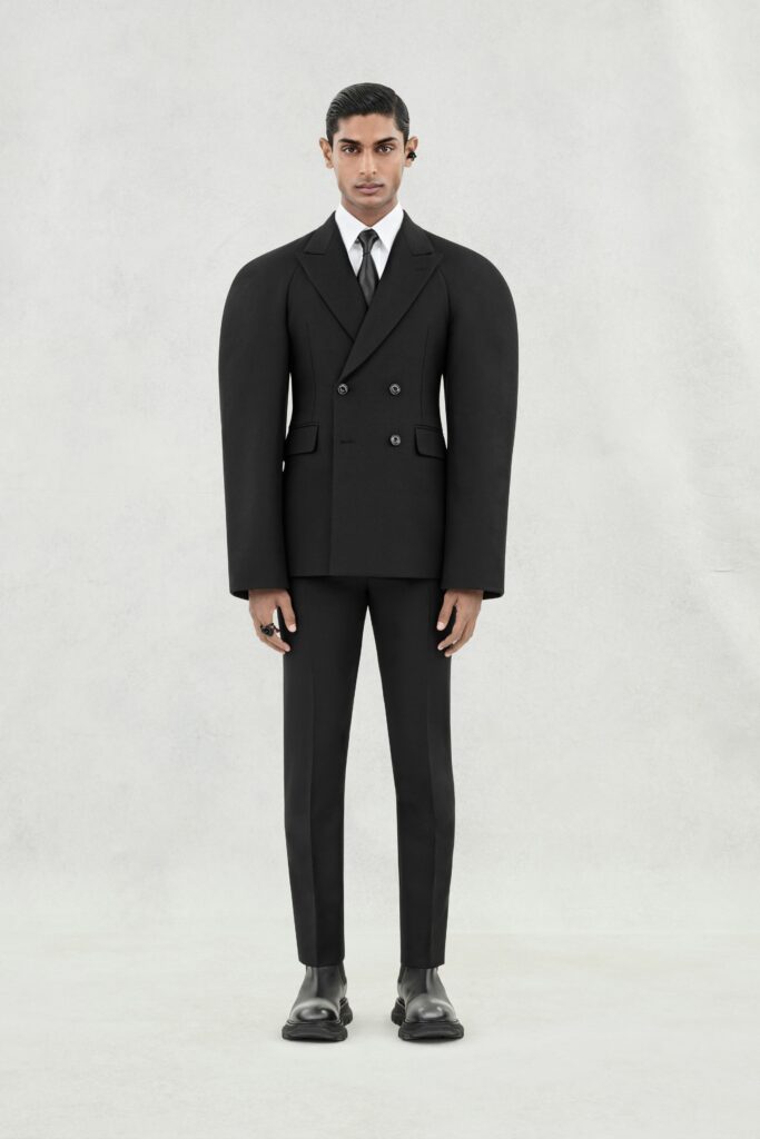 A structured black wool suit featuring a double-breasted design and long sleeves.
