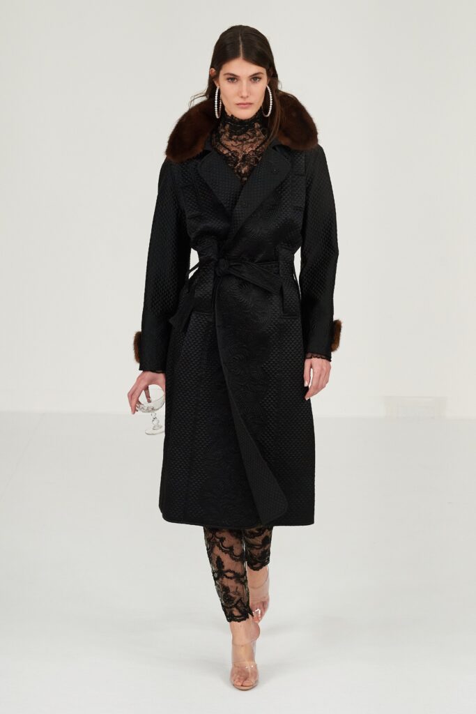 A fitted black silk coat dress with long sleeves and layered sheer details.