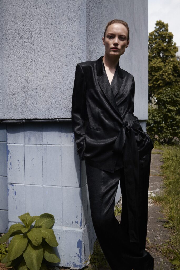 A fitted black silk blazer with long sleeves and tailored pants, offering a sleek silhouette.