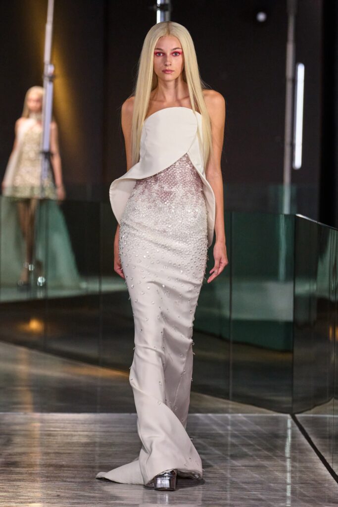 A fitted white silk sleeveless dress with a V-neckline and asymmetric design.