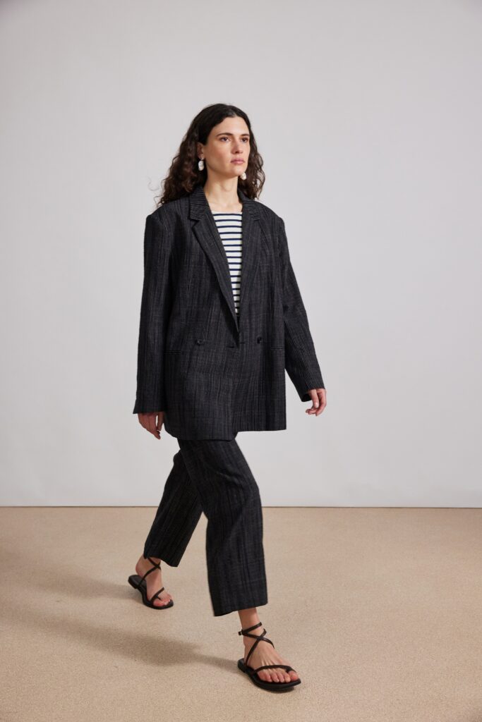 An oversized black blazer paired with striped pants, creating a chic and modern look.