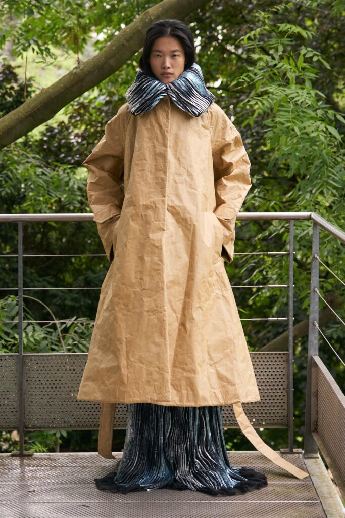 A relaxed brown coat dress with long sleeves, a collared neckline, and an asymmetric layered design.