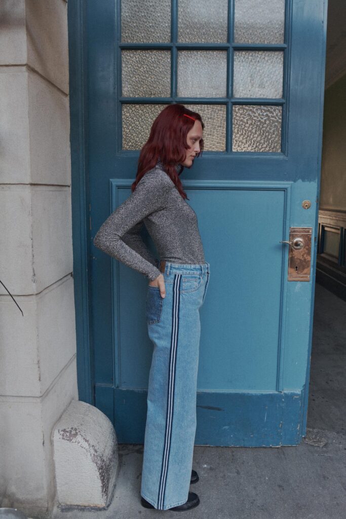 A fitted gray long-sleeve top paired with high-waisted blue jeans featuring a striped detail.
