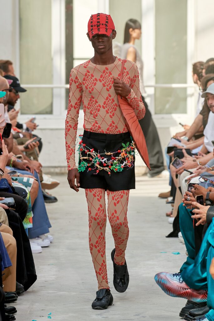 A fitted beige printed bodysuit paired with an asymmetric skirt featuring red accents.