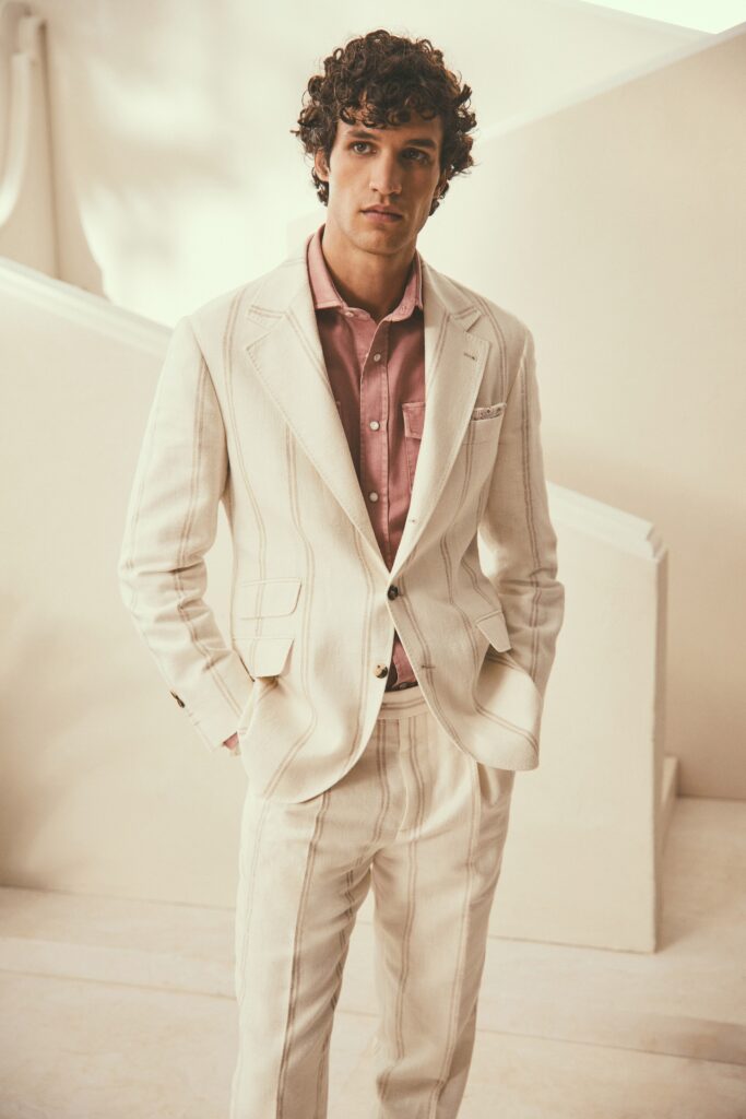 A tailored beige striped suit paired with a pink collared shirt.
