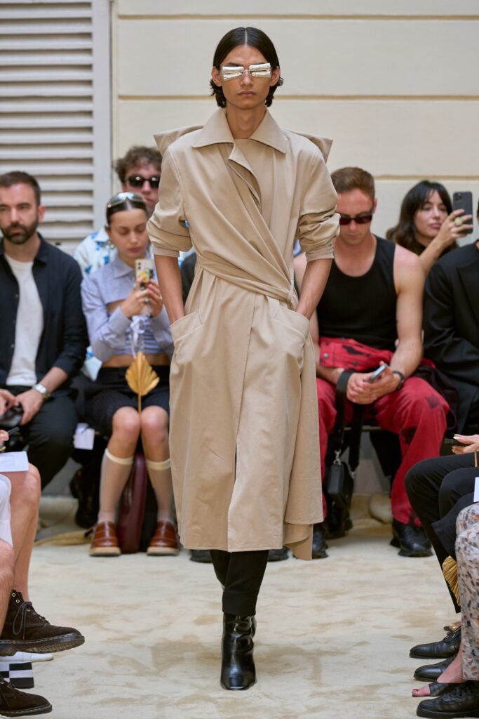 A relaxed beige cotton coat with long sleeves and a belted design detail.