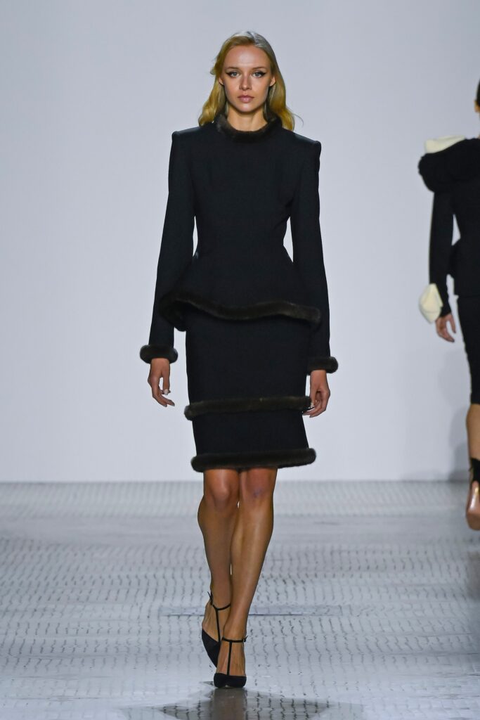 A fitted black wool dress with long sleeves and a high neckline in a pencil silhouette.