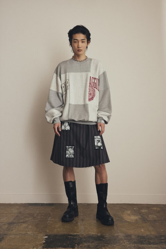 An oversized gray sweater paired with a pleated black skirt for a unique fashion statement.