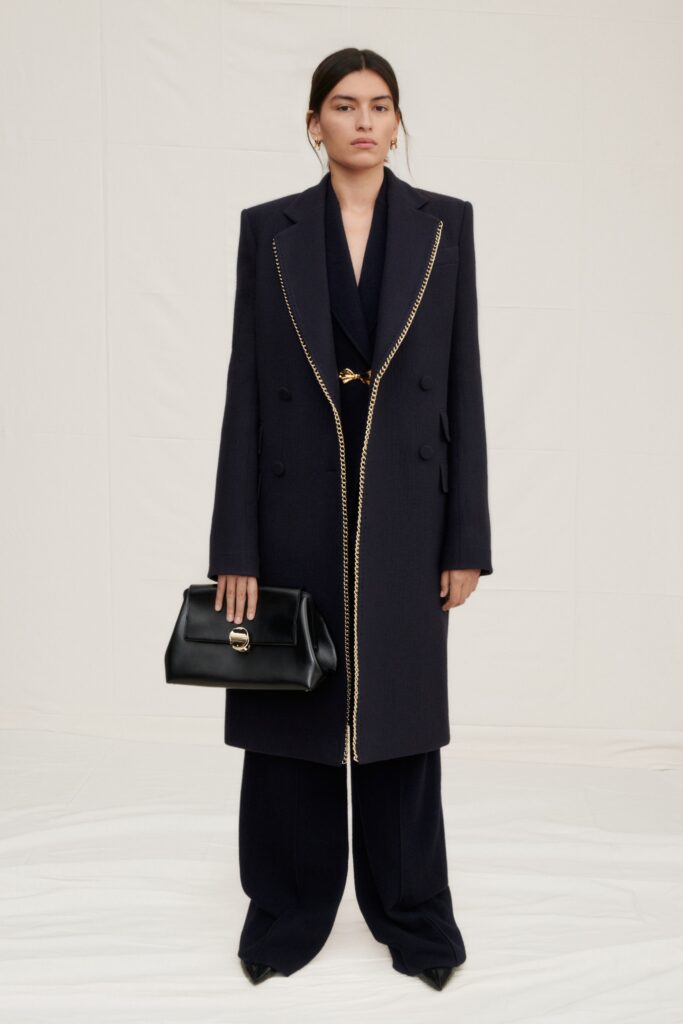 A tailored navy wool coat with long sleeves and a double-breasted design, paired with matching pants.