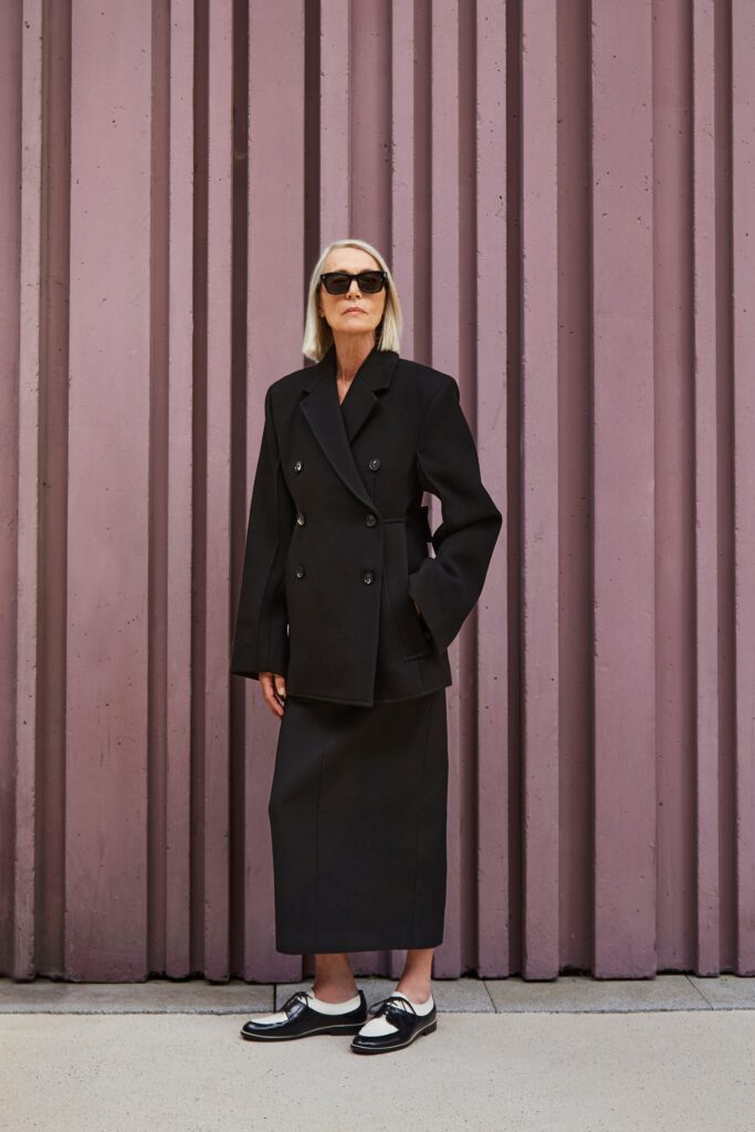 A fitted black wool blazer with a collared design paired with a straight-leg skirt.