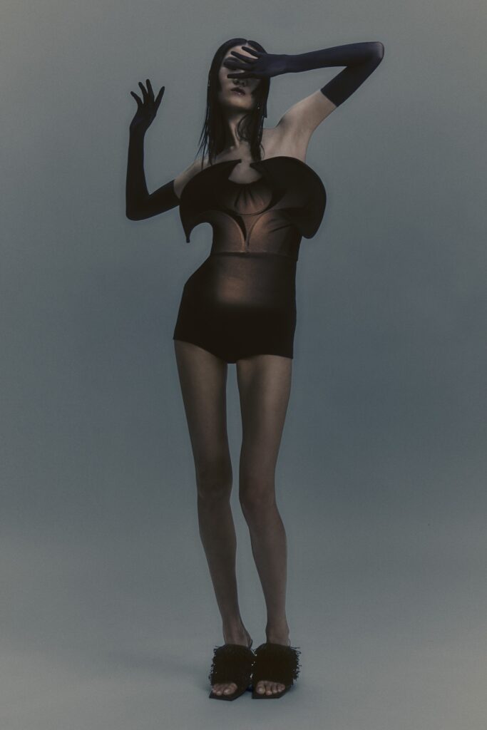 A fitted black silk dress with a sleeveless design and asymmetric cutout details.