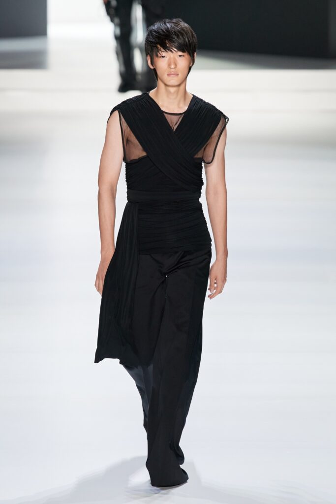 A fitted black silk sleeveless dress with a V-neckline and asymmetric design.