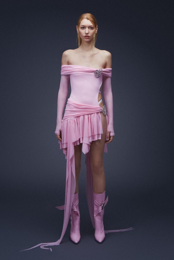 A fitted pink silk dress with an off-shoulder design and asymmetric, tiered details.