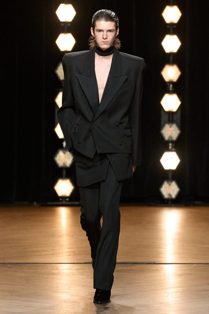 A tailored black wool suit featuring a long-sleeve double-breasted design with a V-neckline.