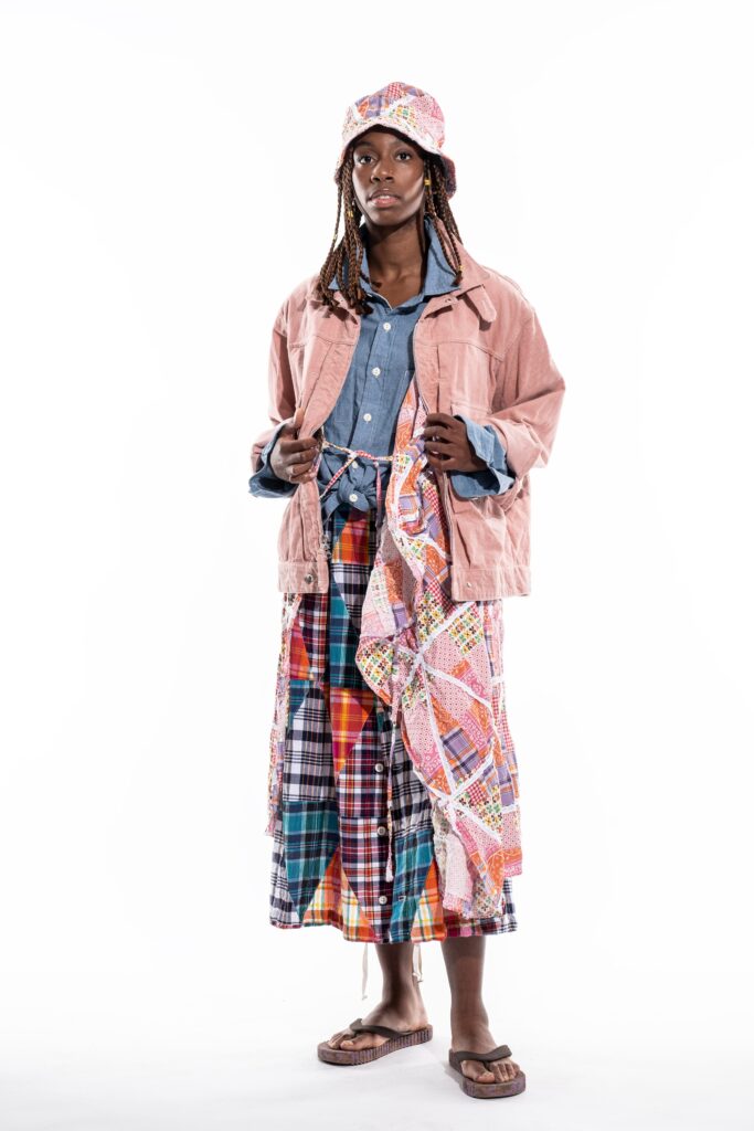 A relaxed pink jacket with a collared long-sleeve shirt and a layered plaid skirt.