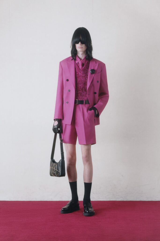 A tailored pink suit with shorts and a collared shirt, featuring buttoned details.