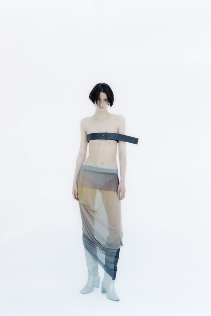 A fitted sheer sleeveless top with an asymmetric layered skirt in gray and beige tones.