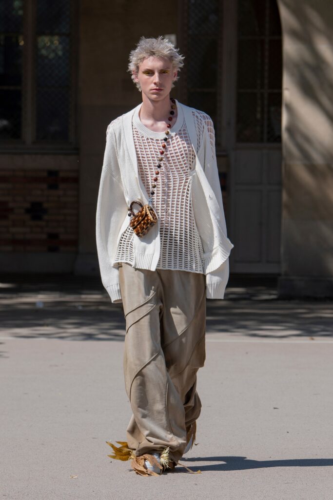 A relaxed white long-sleeve top with a V-neck and beige asymmetric pants.