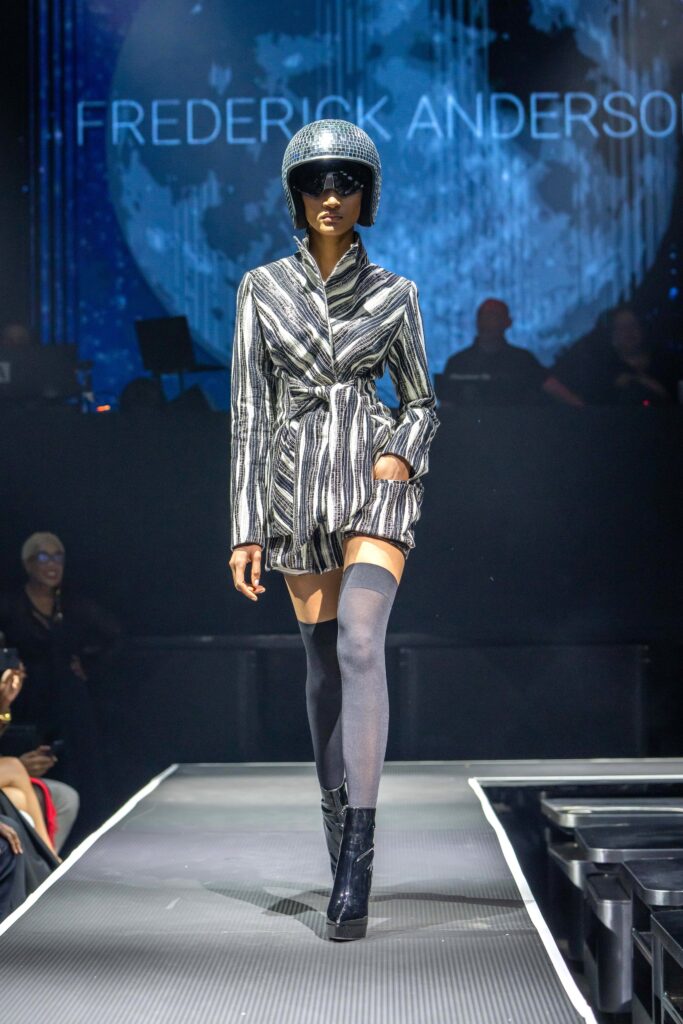 A fitted black and white striped jacket dress with long sleeves and a belted waist.