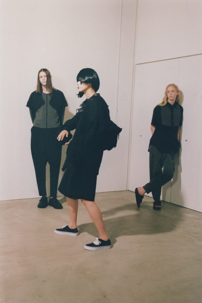 A relaxed black cotton dress with short sleeves and an asymmetric design detail.