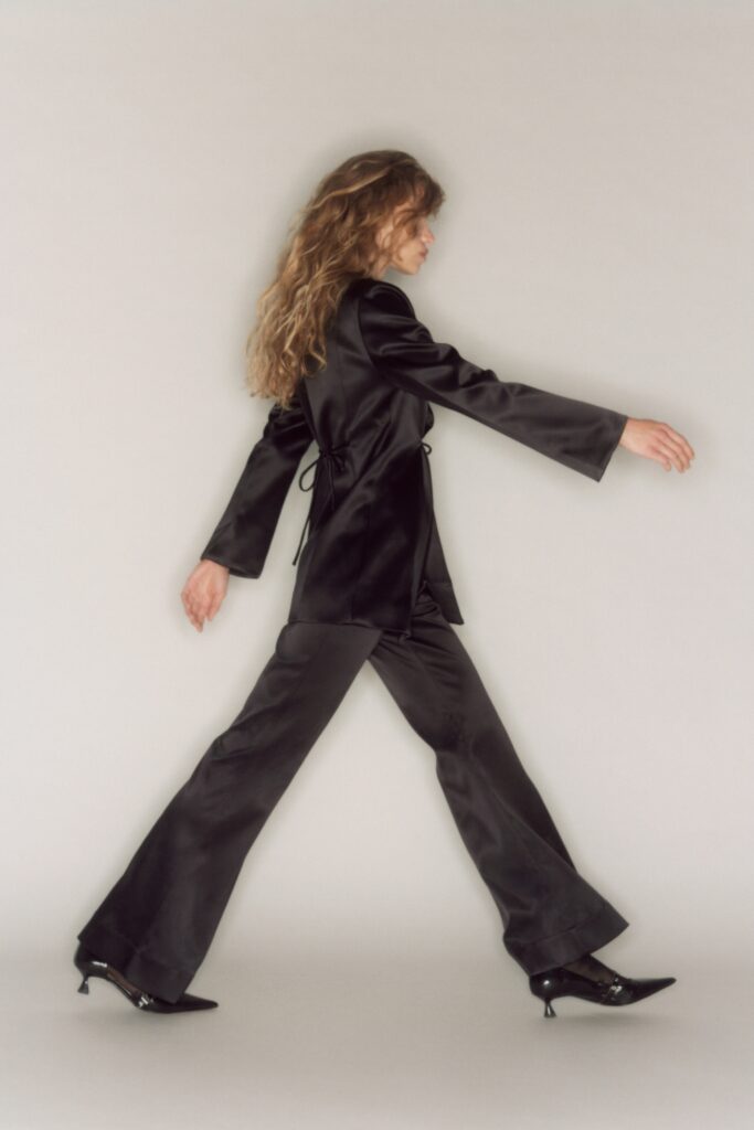 A fitted black silk suit with long sleeves and a flared silhouette.
