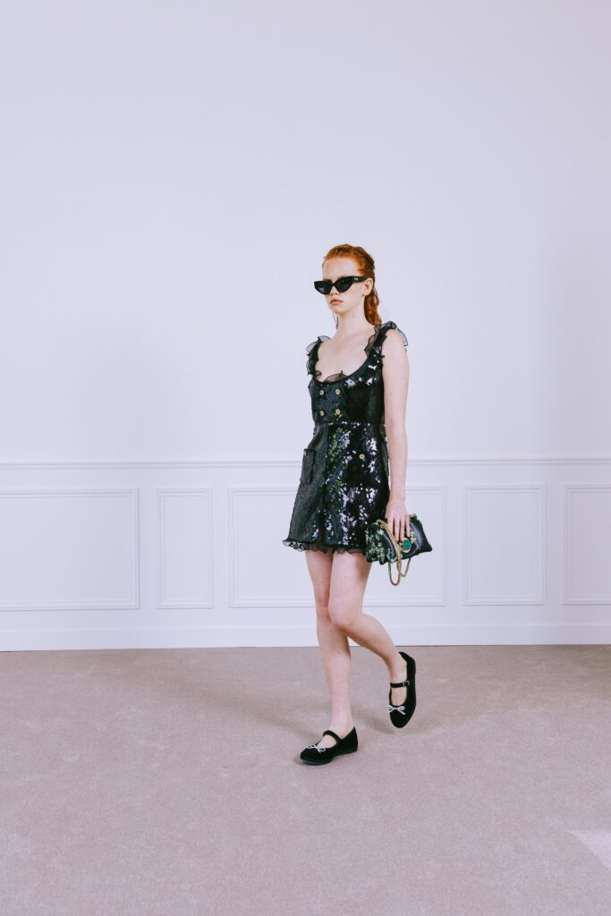 A fitted black sleeveless dress with a V-neckline and ruffled detailing.