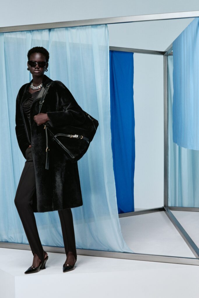 A fitted black fur coat with long sleeves, paired with straight-leg black pants.