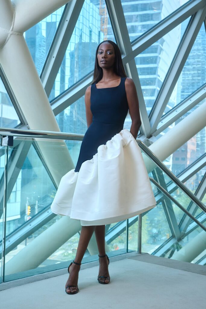 A fitted black and white sleeveless dress with a high neckline and asymmetric design.