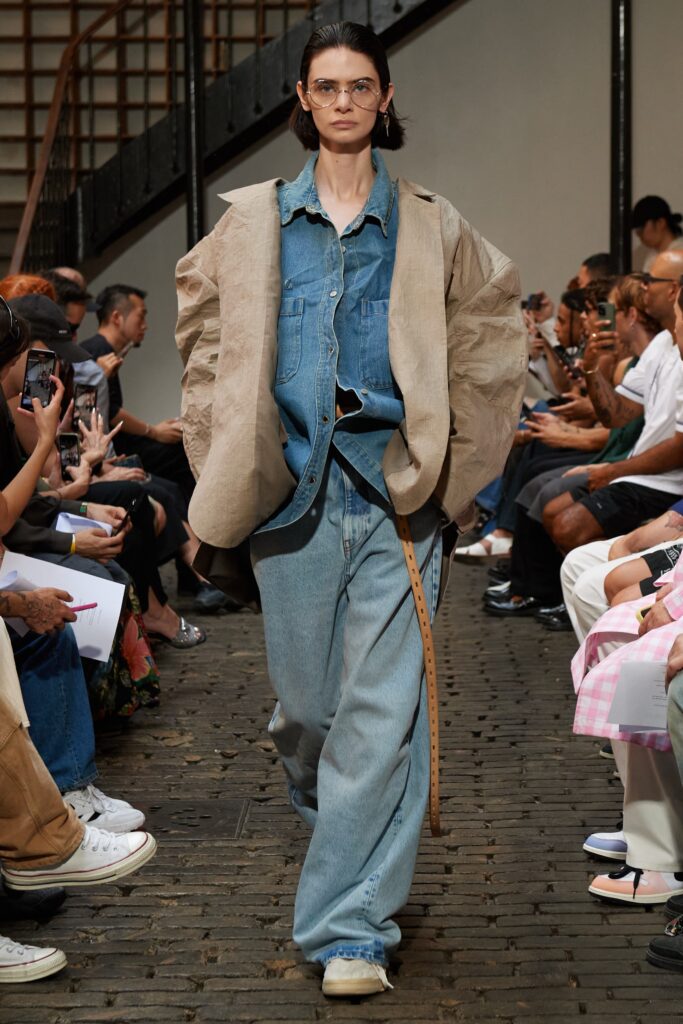 A relaxed-fit denim jacket layered over a collared shirt with wide-leg jeans.