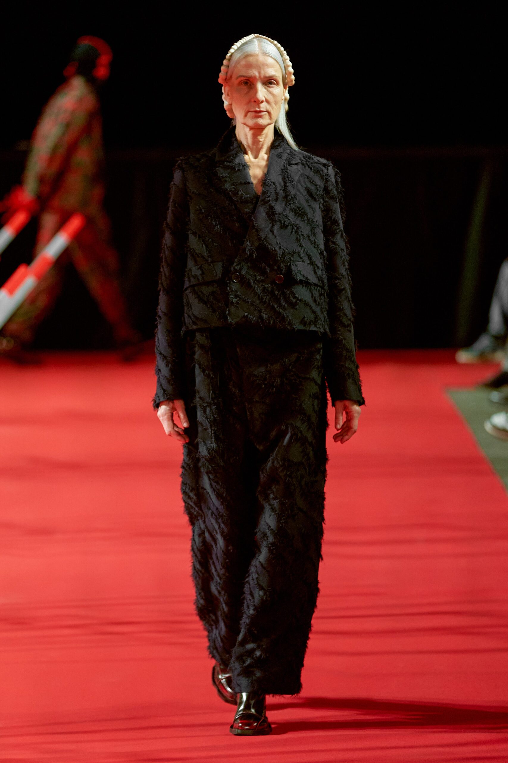 A fitted black silk suit with long sleeves, a collared design, and embroidered details.