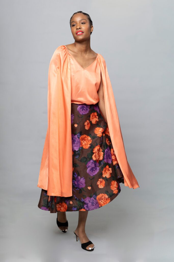A fitted orange silk sleeveless top paired with a flared brown floral skirt.