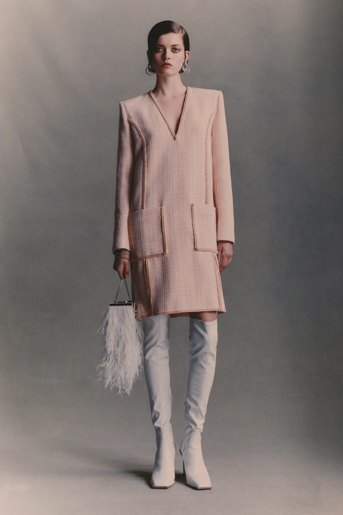 A relaxed beige tweed long-sleeve dress with a V-neckline and straight-leg silhouette.