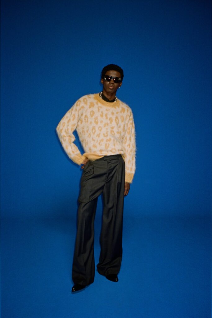 A relaxed beige printed knit sweater paired with black relaxed-fit pants.