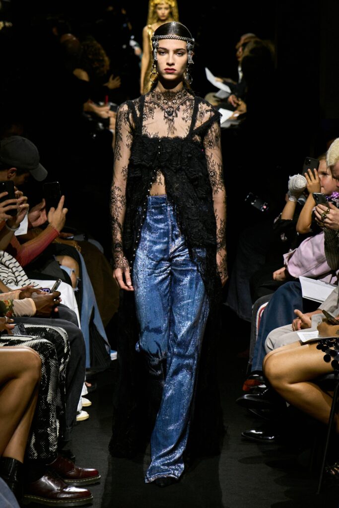 A relaxed black lace sleeveless top paired with flared blue denim pants.