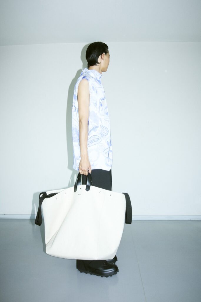 A relaxed white sleeveless shirt with a printed design paired with black pants.