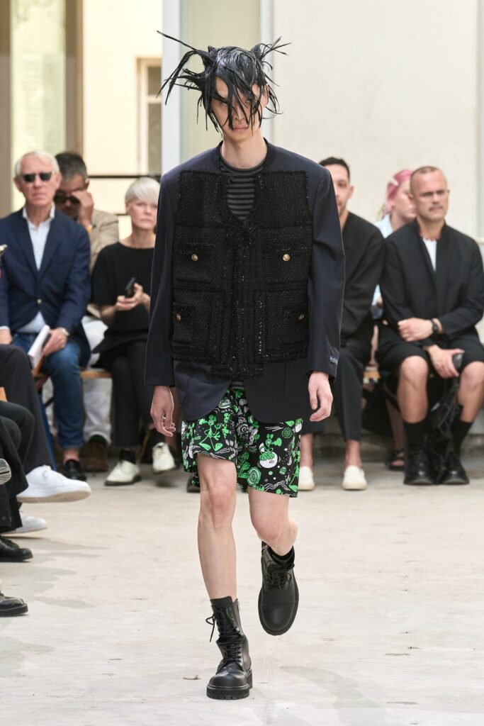 A relaxed black jacket paired with green printed shorts, creating a bold fashion statement.