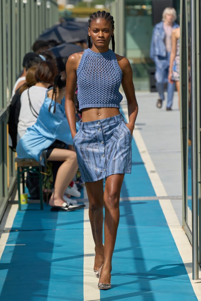 A fitted blue cotton sleeveless top with a collared design paired with a striped skirt.