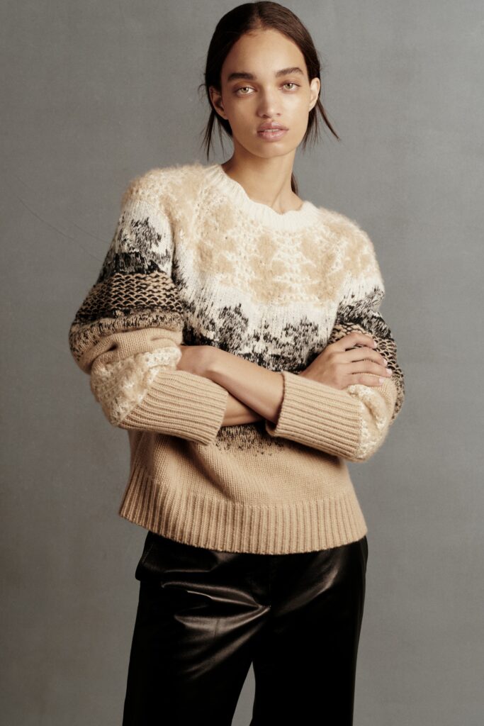 A relaxed-fit beige wool sweater with long sleeves paired with sleek black leather pants.