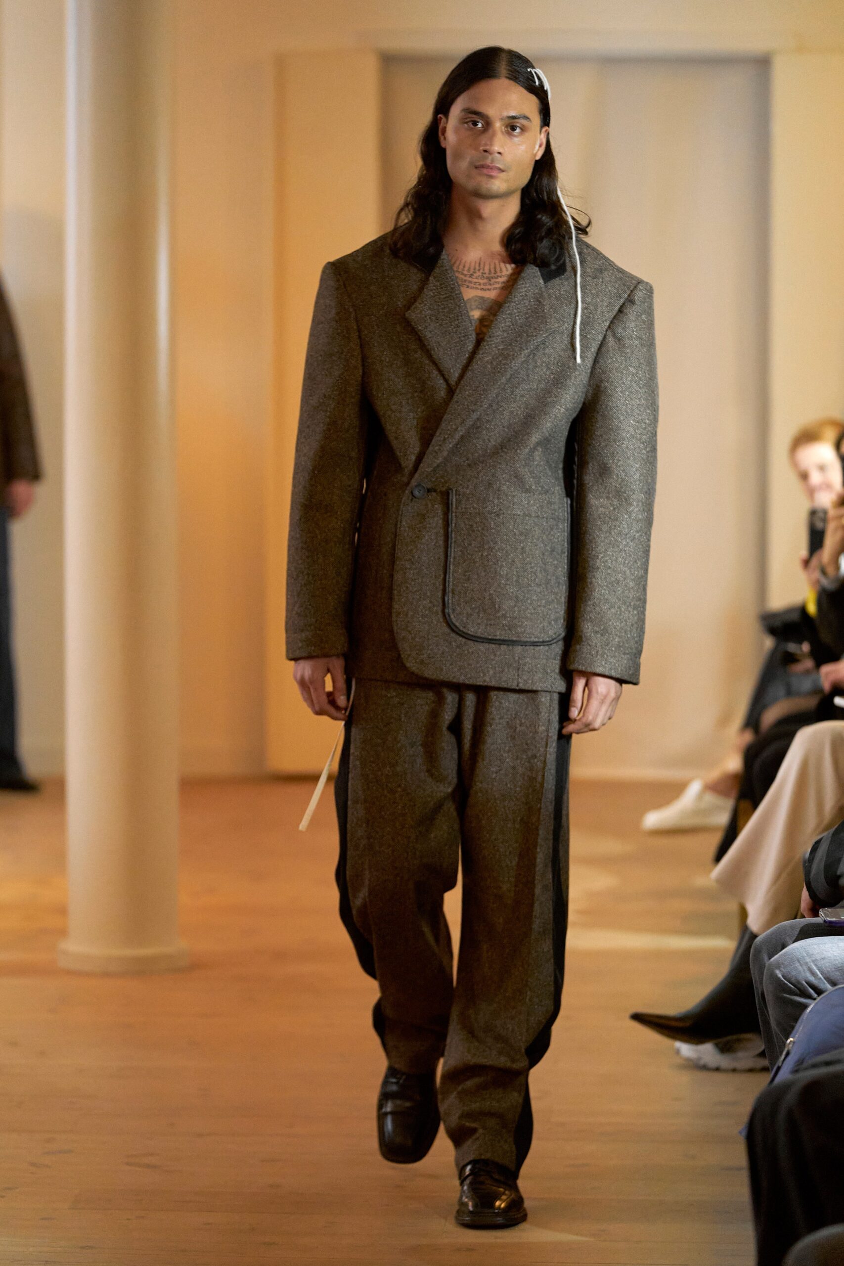 A tailored brown wool suit with long sleeves and a buttoned design featuring straight-leg trousers.