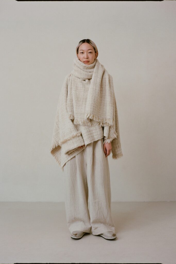 A relaxed beige wool poncho paired with loose-fitting cotton pants for a comfortable look.