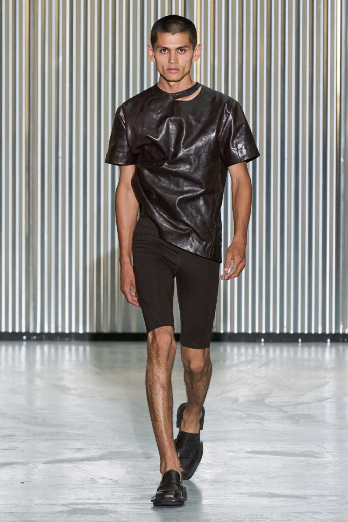A fitted black leather short-sleeve top paired with matching fitted shorts featuring an asymmetric design.