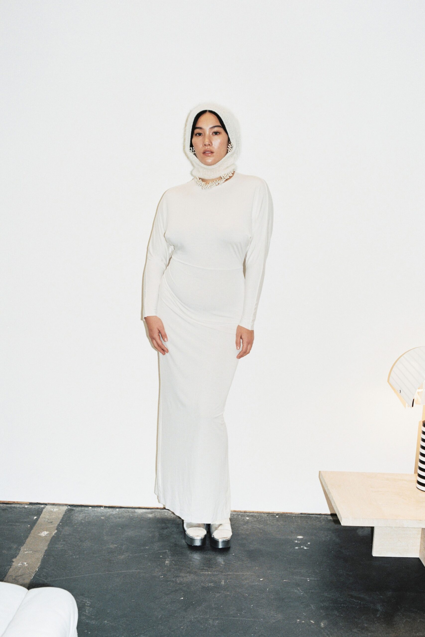 A fitted white long-sleeve dress with a high neckline and straight-leg silhouette.
