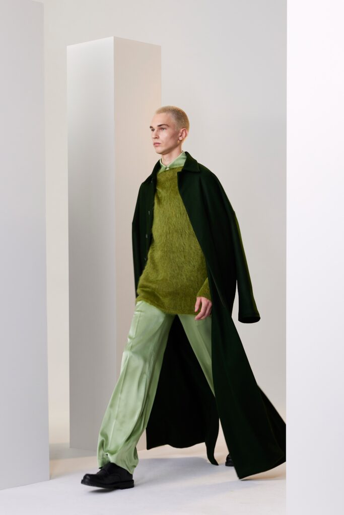 A relaxed green wool coat layered over a light green top with long sleeves and a collared design.