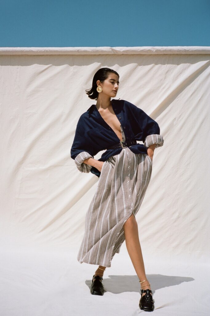 A relaxed blue and white striped dress with a V-neckline and buttoned front featuring a slit.