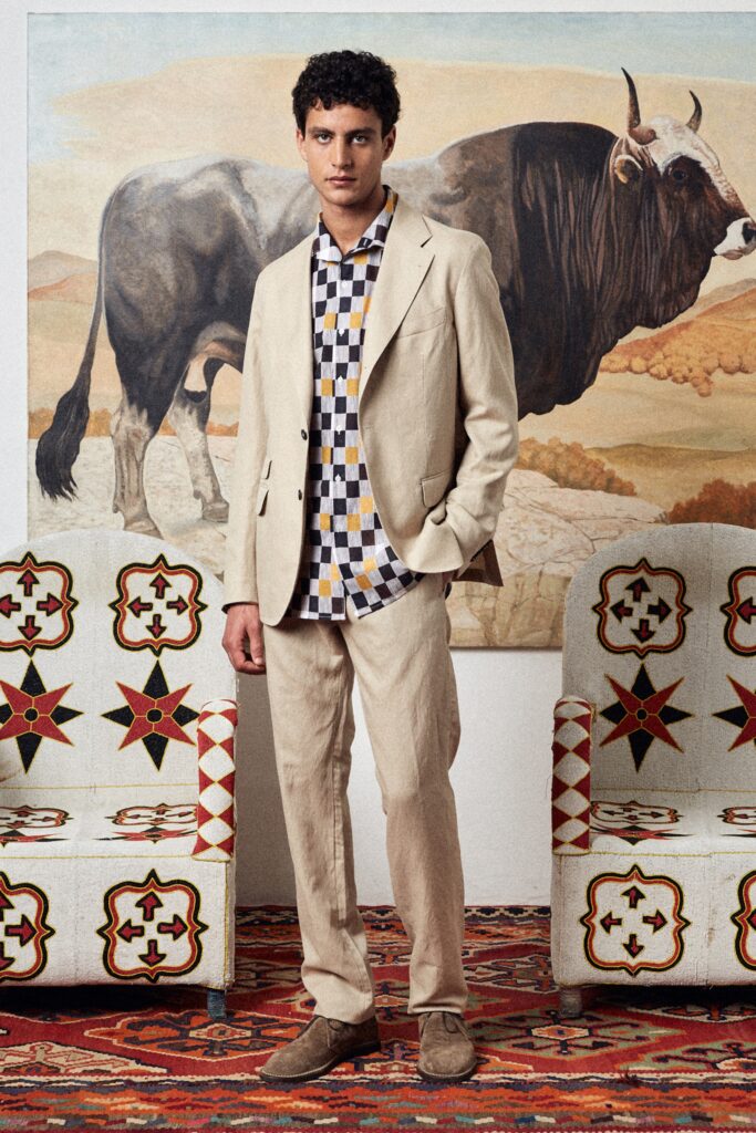 A tailored beige suit paired with a long-sleeve collared checked shirt.