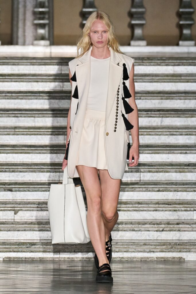 A fitted beige sleeveless dress paired with a stylish collared jacket featuring layered details.